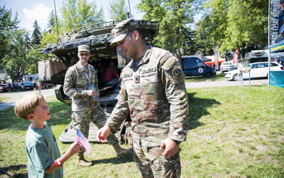Americký voják předává vlajku USA před obrněným transportérem Stryker